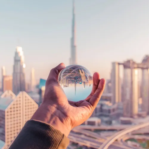 Mano que sostiene una bola de cristal que refleja el horizonte de una ciudad