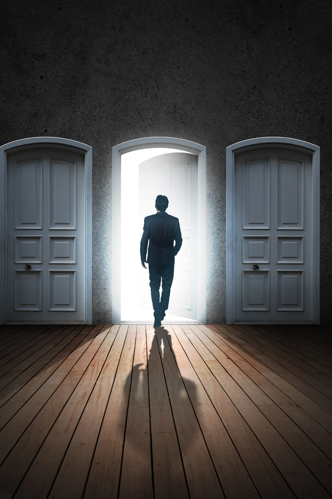 Un uomo d’affari attraversa una porta aperta e illuminata tra due porte chiuse
